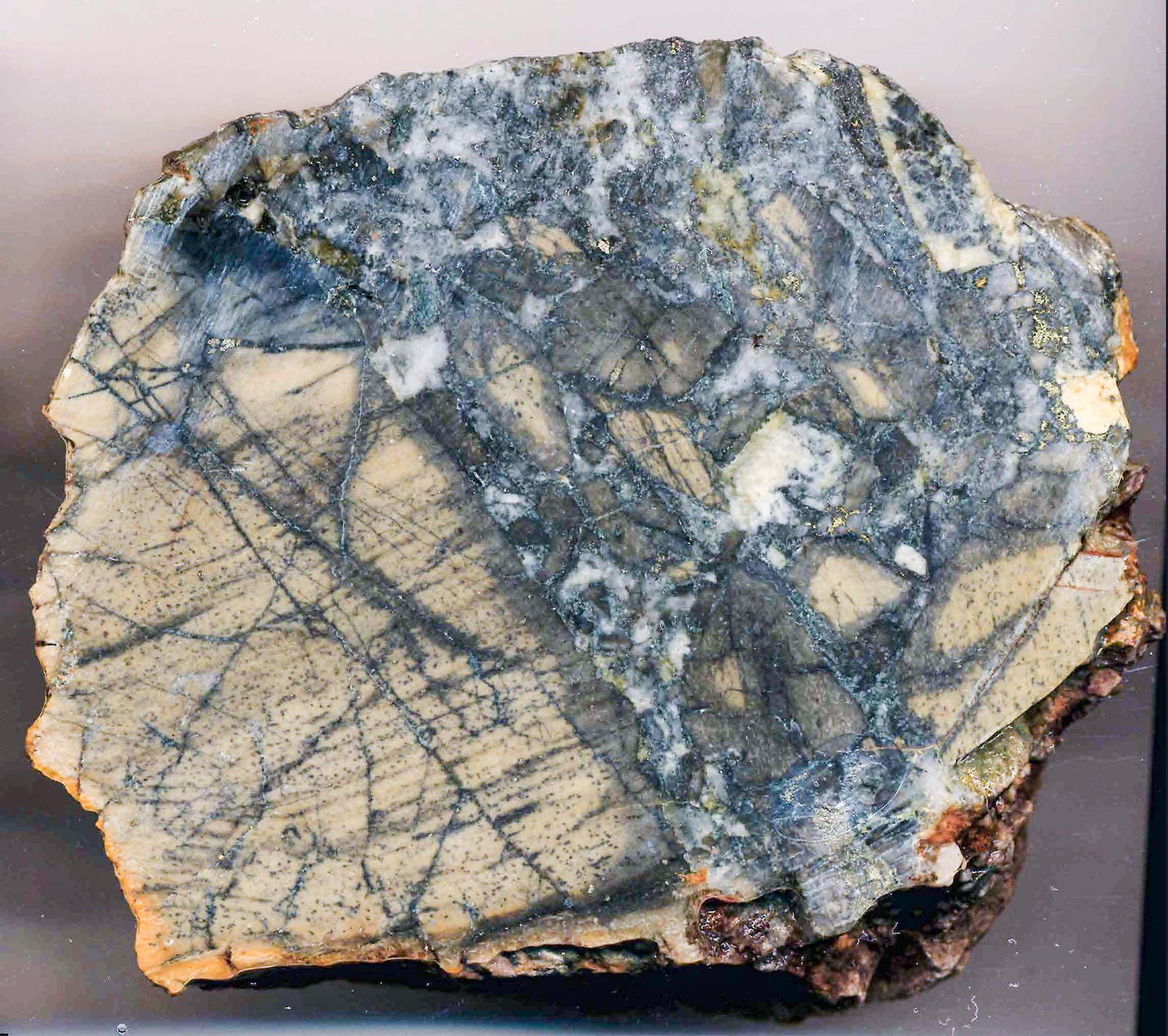 Sample P1. Buff-coloured, bleached basalt pervasively stockwork fractured grading to brecciated with in-fillings of coarse white quartz and patchy disseminations of pyrite and glaucodot.